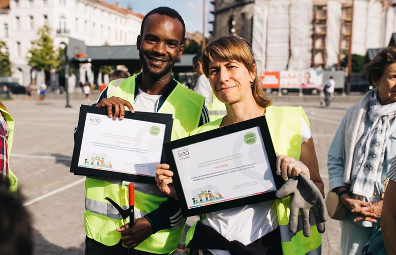 Two volunteers with certificates after clean-up event.