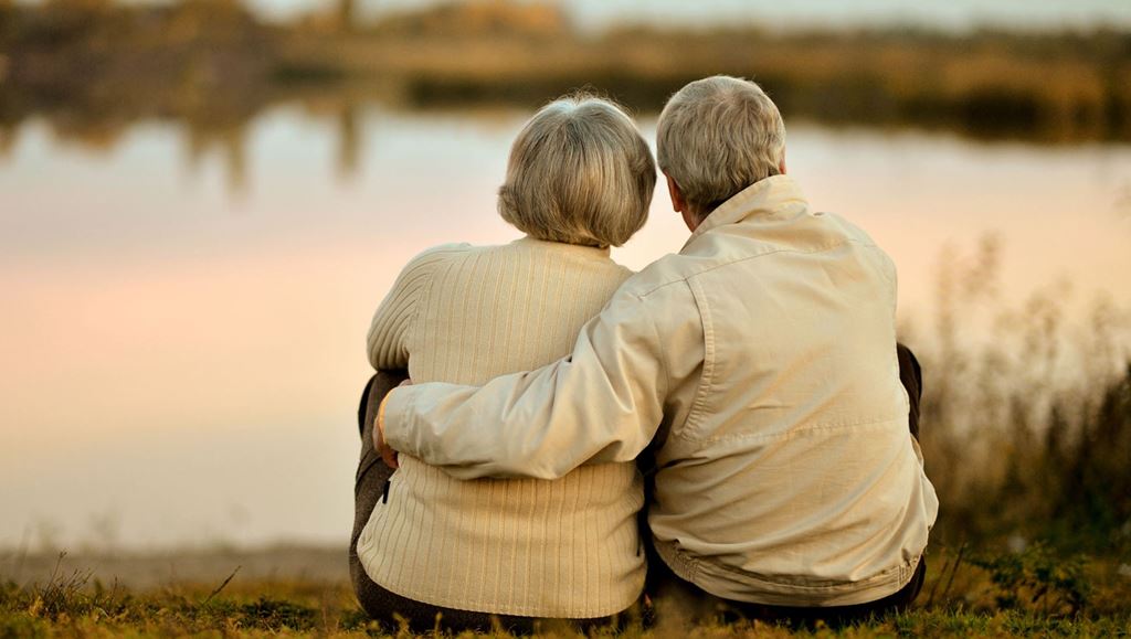 Elderly couple embracing looking out at a lake