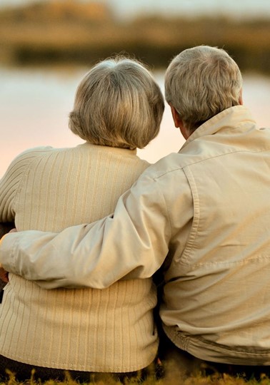 Elderly couple embracing looking out at a lake