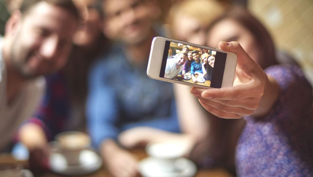 Lady taking a selfie with a small group of people