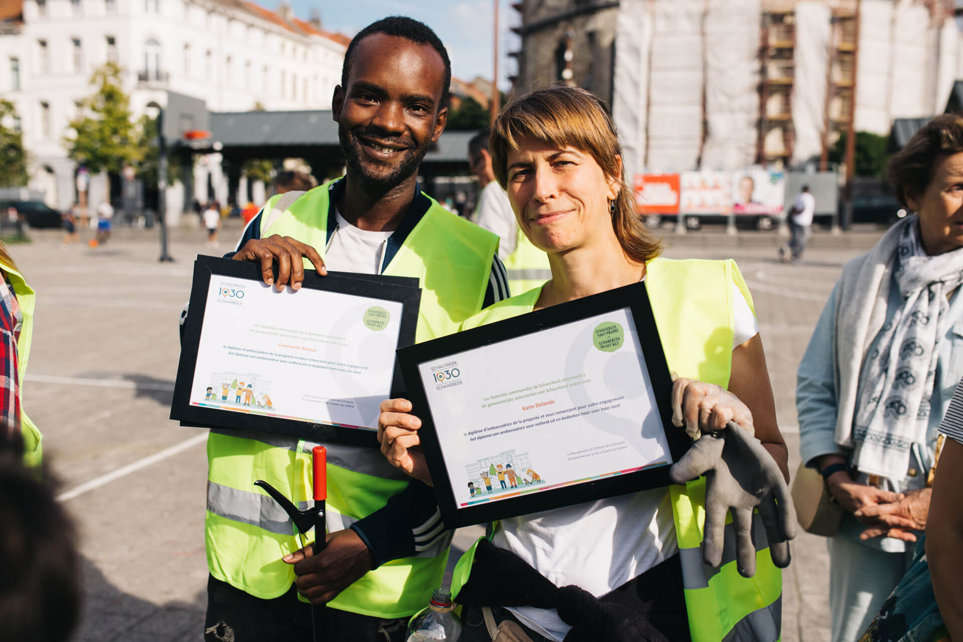 Two volunteers with certificates after clean-up event.