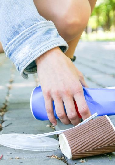 Female hands picking up trash outdoors in the street in summer