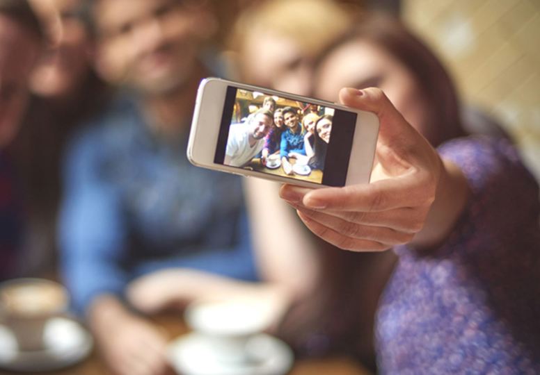 Lady taking a selfie with a small group of people