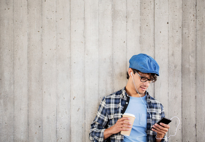 New podcast to promote EU-funded research Young man in blue hat holding coffee and phone listening to a podcast