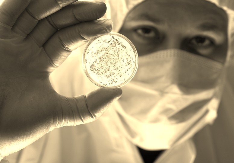 Man in protective lab gear holding petri dish