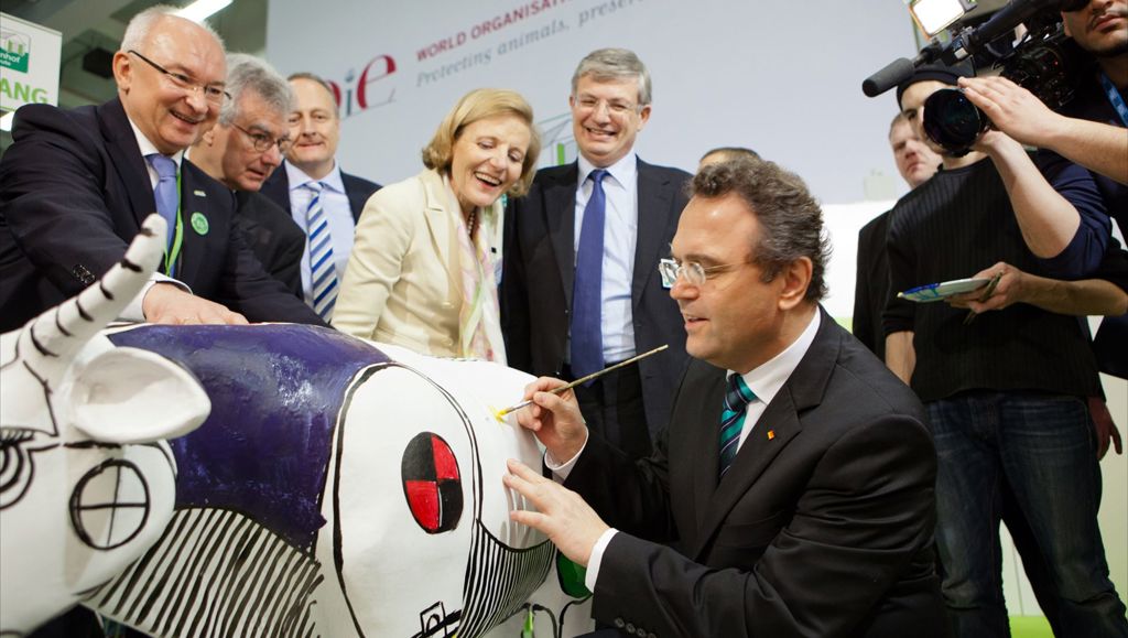 Business people watching a colleague paint on a large ornamental cow