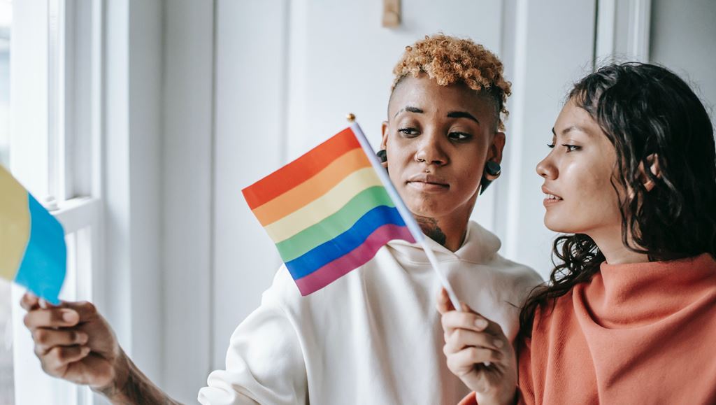 Diverse Lesbian Couple With Pride Flags
