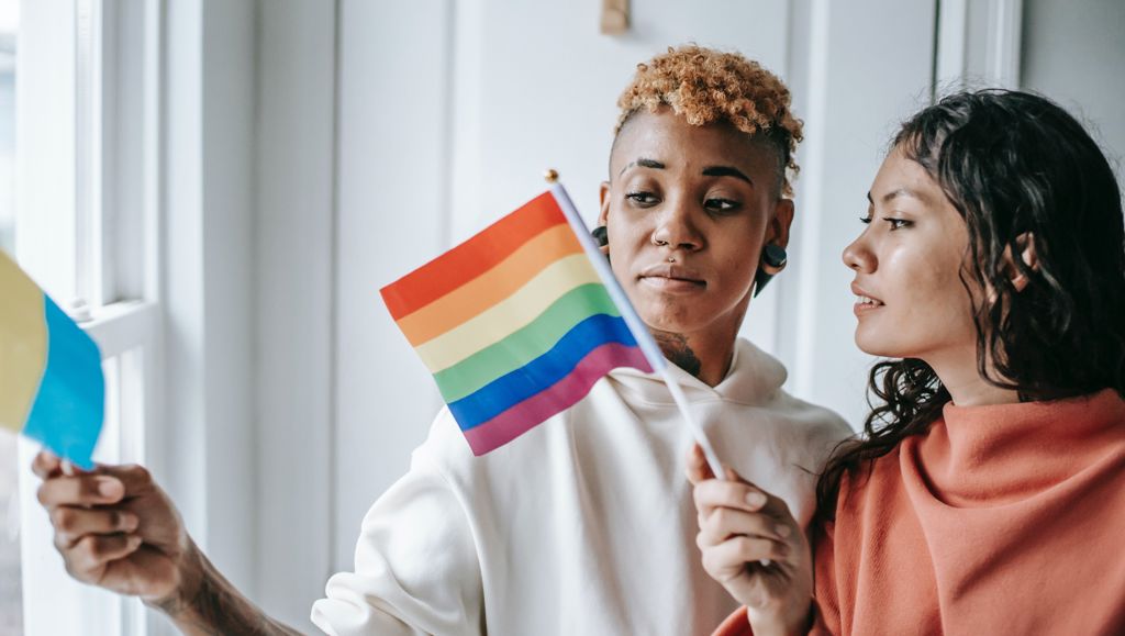 Diverse Lesbian Couple With Pride Flags