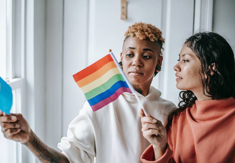 Diverse Lesbian Couple With Pride Flags