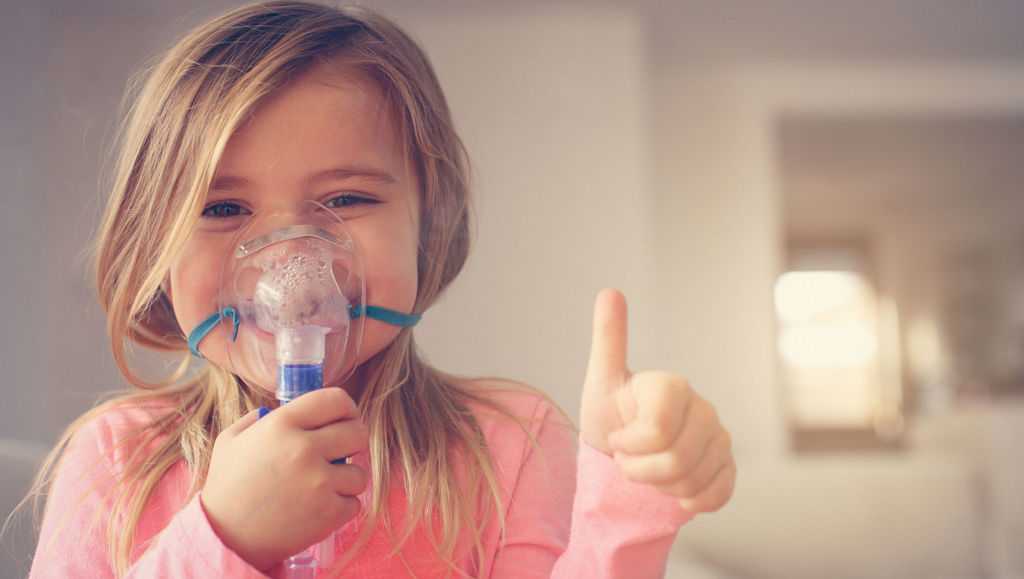 Little girl using inhaler and showing OK.