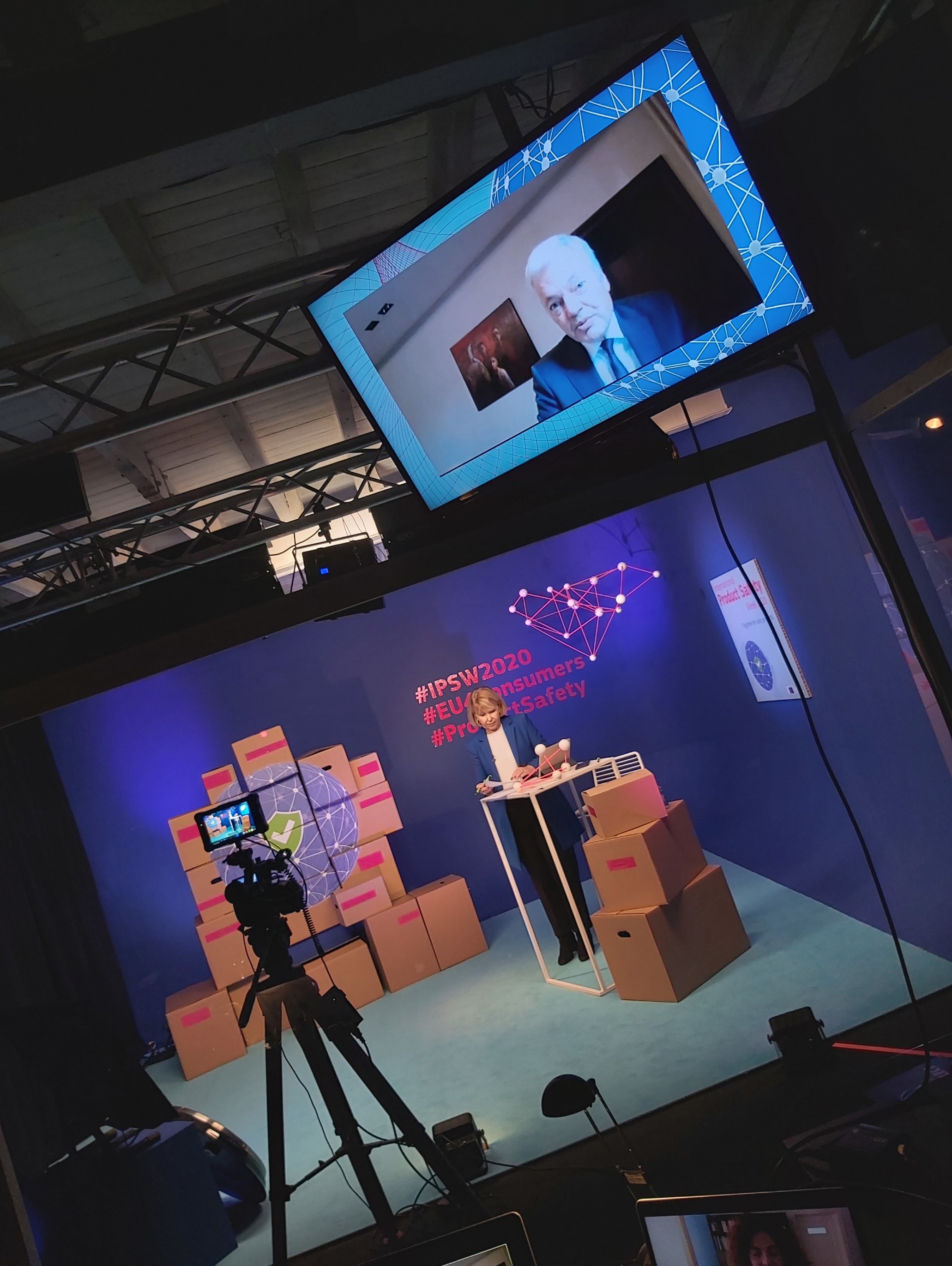 Moderator in studio with Commissioner Reynders on screen.