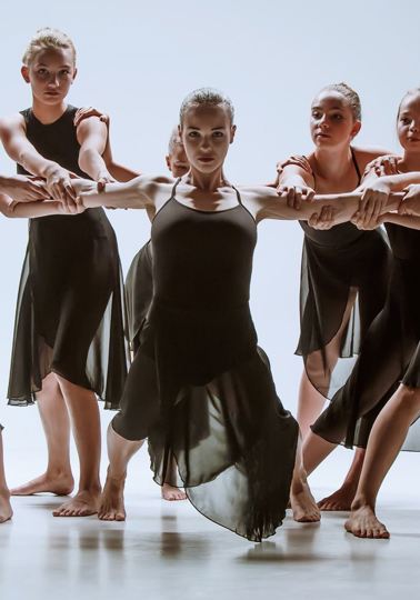 The group of modern ballet dancers dancing on gray studio background