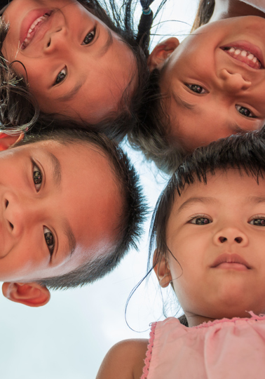 Group of Indonesian children hugging and looking down into the camera smiling