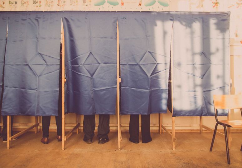 Designing the Brussels elections website People at polling station voting behind curtain